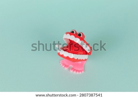 Playful Red Wind-Up Chattering Teeth Toy on a Mint Green Background