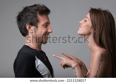 Playful taps on her boyfriend's chest, a young woman's childlike teasing brims with love. He tolerantly accepts, their mutual respect evident. This lively scene hints at forthcoming emotional, laughte