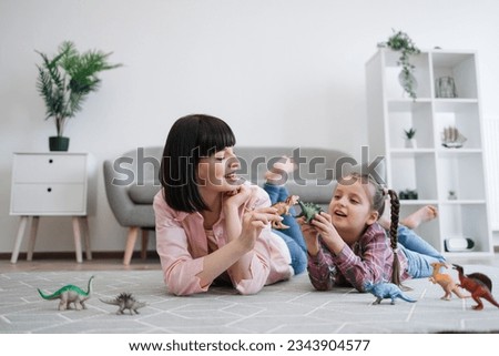 Playful tween girl with animal toy having fun with brunette woman in living room of spacious apartment. Mindful mother encouraging scientific exploration while keeping daughter entertained indoors.