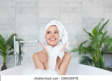 Playful vivacious emotional happy woman taking bath with foam. 