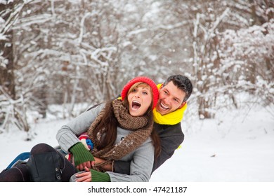 Playful winter couple sledding on sled in park