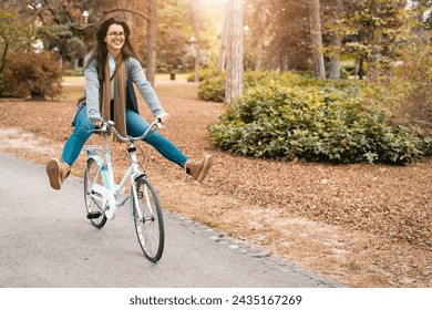 Playful young adult female tourist riding rented bike in the city park while exploring a new town. - Powered by Shutterstock