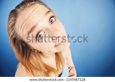 A playful young blonde makes a humorous face, looking confused