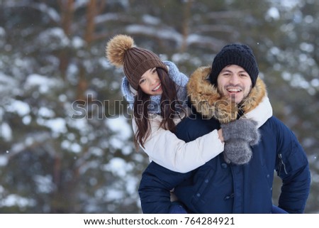 Playful young couple walking in snowy winter forest. Blur background, copyspace