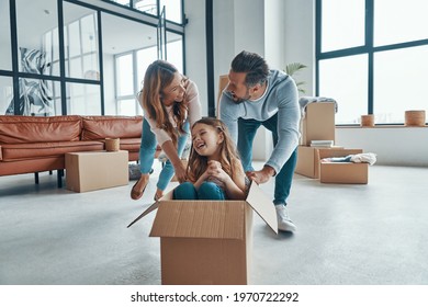 Playful Young Family Smiling And Unboxing Their Stuff While Moving Into A New Apartment