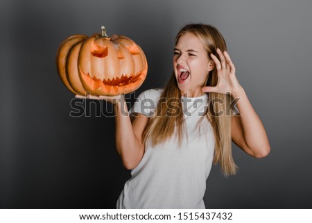 playful young woman with halloween jack o lantern pumpkin isolated over grey