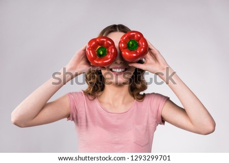 Playfull girl posing with red peppers isolated on white background.