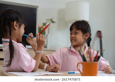 Playfulness and Fun. Two girls enjoying a playful moment with colored pencils.