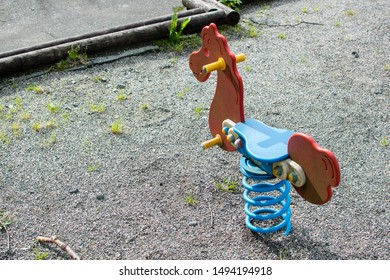 Playground Equipment In A Used Or Older State. A Bouncy Horse In Red And Blue. 