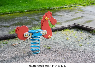 Playground Equipment In A Used Or Older State, A Bouncy Horse In Red And Blue. 