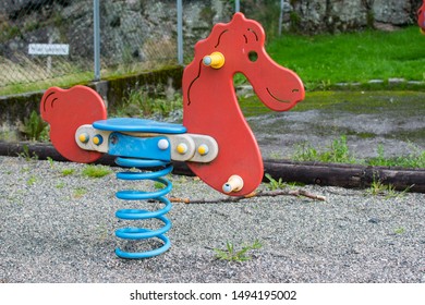 Playground Equipment In A Used Or Older State, A Bouncy Horse In Red And Blue. 