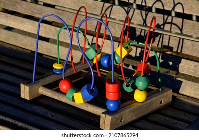 Playground Fencing Made Of Galvanized Railings With A Gate Against Dogs. Community Sandpit With Donated Colorful Puzzle Toys. Bordered By Wooden Beams Around The Sand And Logs Like Benches