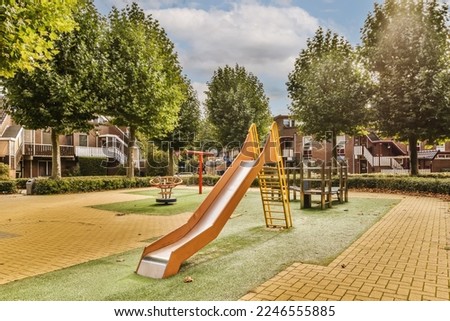 a playground with a slide in the middle school's play area, surrounded by trees and green lawns