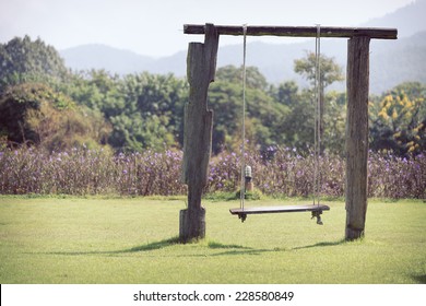 playground swing made wood hanging in green grass field