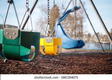 Playground Swing Set For Toddlers With Natural Wood Mulch Ground For Save. Selective Focus On Yellow Full Bucket Seat. 