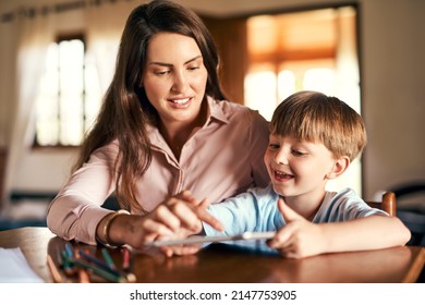 Playing An Active Role In The Learning Process. Shot Of A Little Boy Using A Digital Tablet While Doing Homework With Help From His Mother.