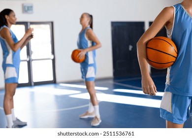 Playing basketball, female athletes holding basketballs and standing in gym, copy space. Sports, competition, teamwork, fitness, women, athletic - Powered by Shutterstock