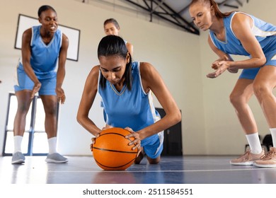 Playing basketball, female team encouraging teammate doing push-ups with ball. Sports, teamwork, fitness, encouragement, exercise, training - Powered by Shutterstock