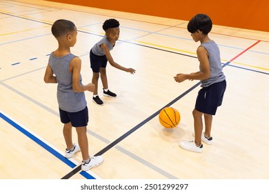 Playing basketball in school gym, three boys practicing dribbling and passing. Sports, teamwork, practice, gymnasium, exercise, fitness - Powered by Shutterstock