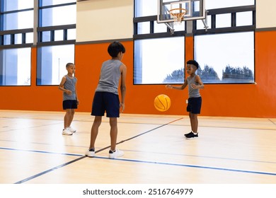 Playing basketball, three multiracial boys practicing in school gymnasium, wearing sportswear. athletics, teamwork, practice, youth, exercise, fitness - Powered by Shutterstock