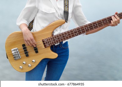 Playing the bass guitar. The hand of the girl playing the bass guitar outside. - Powered by Shutterstock