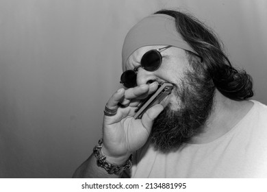 Playing blues with harmonica, wearing a hair band, skull bracelet, rings and sunglasses