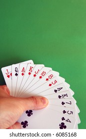 playing bridge - one hand (Q spade, J heart, A,K,J,10,8,3 diamonds, A,K,7,5,4 clubs)  background green, selective focus