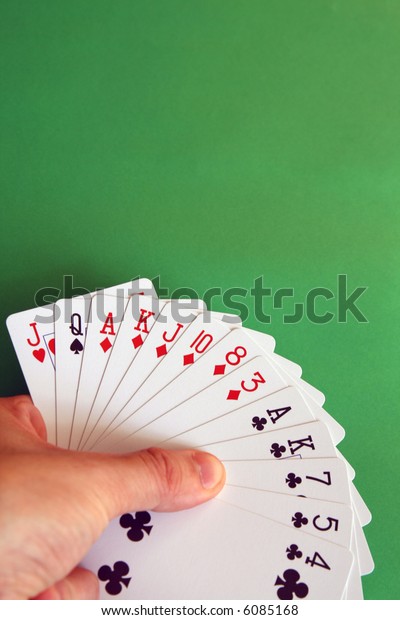 playing bridge - one hand (Q spade, J heart,\
A,K,J,10,8,3 diamonds, A,K,7,5,4 clubs)  background green,\
selective focus