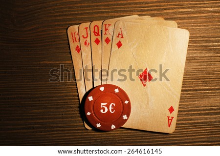 Playing cards with chips on wooden background