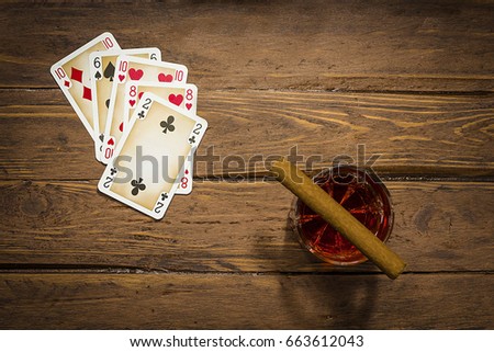 Playing cards, cigar and drink on the old boards