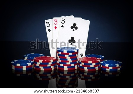 Playing cards in poker game with three of kind or set combination. Chips and cards on black table. Successful and win.