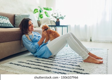 Playing with cat at home. Young woman sitting on carpet and hugging pet. - Powered by Shutterstock