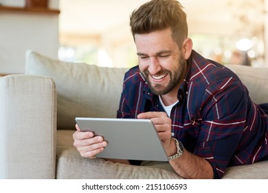 Playing Catch Up With Life Online. Shot Of A Relaxed Young Man Using A Digital Tablet On The Sofa At Home.