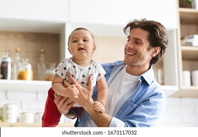 Playing with daddy. Young father raising his baby son like on plane at kitchen