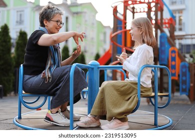 Playing with a deaf child, a woman communicates with a girl in sign language. - Powered by Shutterstock