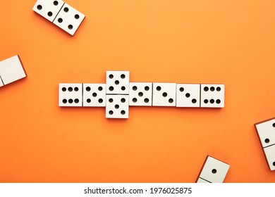 Playing Dominoes On A Orange Table. Domino Effect. Top View