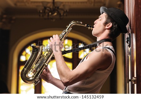 Playing funky music. Handsome young jazzmen playing sax with his eyes closed