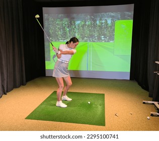Playing golf on screen and golf simulator. Young golfer playing golf video game indoors - Shutterstock ID 2295100741