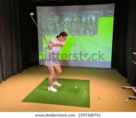 Playing golf on screen and golf simulator. Young golfer playing golf video game indoors