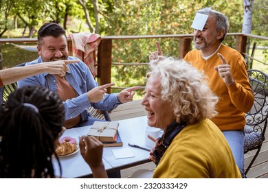 Playing Guessing game using sticky notes on forehead, having fun with friends on a porch in sunny spring day. Copy space - Powered by Shutterstock