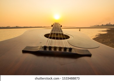 Playing guitar against sunset at the beach of Mekong river - Powered by Shutterstock