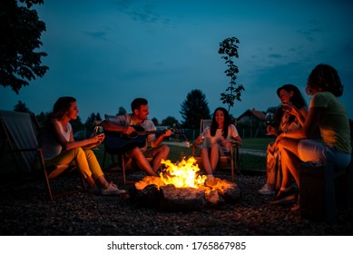 Playing guitar and singing around the bonfire at night.