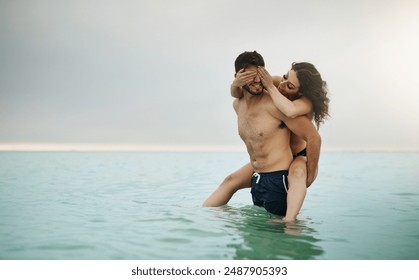 Playing, piggyback or happy couple at sea to travel for love on vacation, valentines day or holiday. Eyes closed, peekaboo mockup or people swimming for bonding at beach on romantic trip on island - Powered by Shutterstock