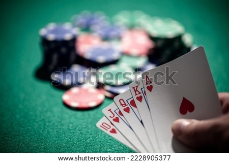 Playing poker in a casino holding winning royal flush hand of cards concept for gambling, betting and winning