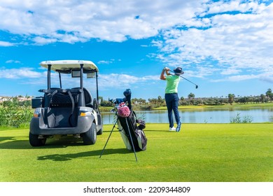 Playing professional golf on golf course, hitting the ball by a lake, buggy - Powered by Shutterstock