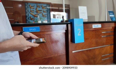 Playing Smartphone In Front Of A Bank Teller