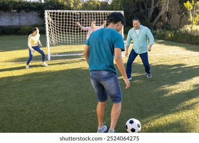 Playing soccer, family enjoying outdoor activity together on grassy field. fun, bonding, sports - Powered by Shutterstock