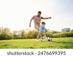Playing soccer. Happy father with son are having fun on the field at summertime.