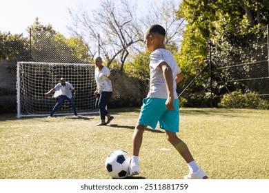 Playing soccer outdoors, boy kicking ball towards goal with grandparents and grandson watching. sports, recreation, teamwork, action - Powered by Shutterstock