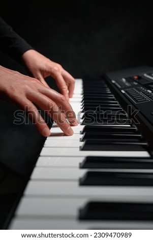 Playing a synthesizer on a dark background. The musician plays the synthesizer.